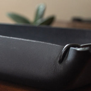 A view of a black, oblong tray crafted by hand from Italian full-grain leather.