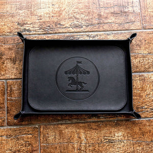 Black leather tray with carousel design on a wooden surface