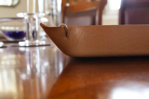 View of a natural-colored, large size Italian leather tray with leather cords at each corner