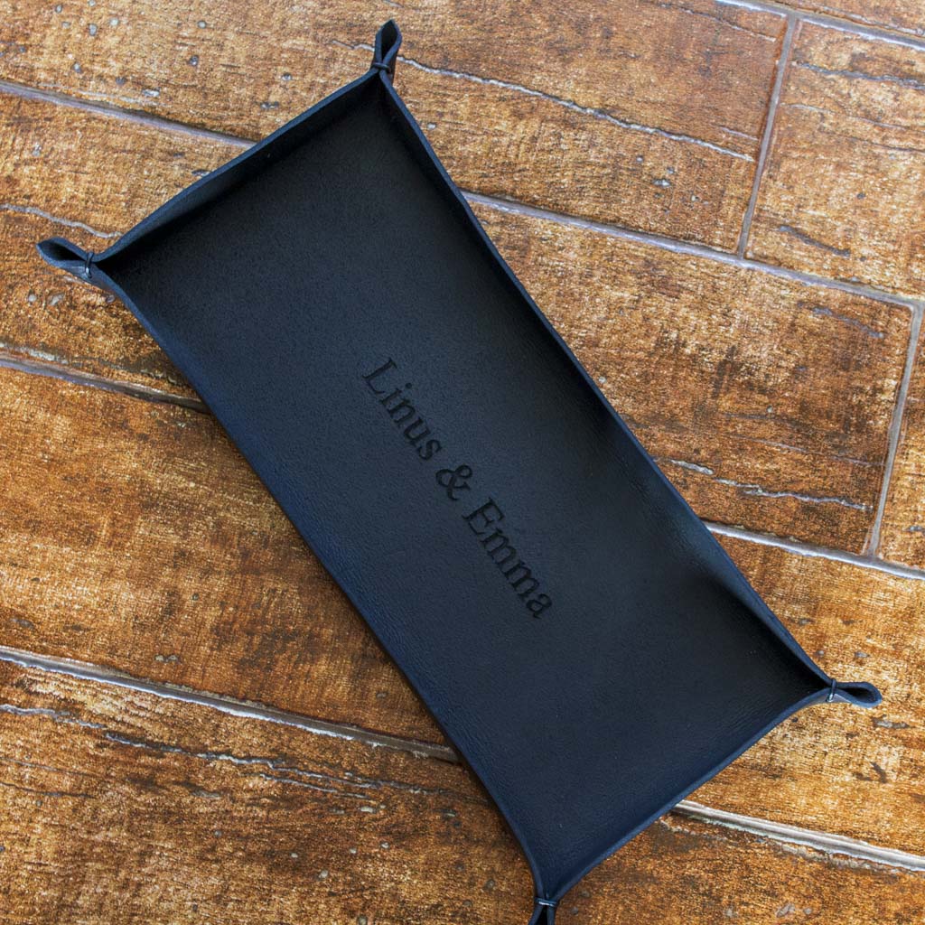 Black, oblong tray crafted by hand from Italian full-grain leather, personalized with engraved names