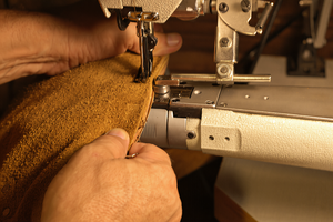 Close-up of a sewing machine in use with leather being sewn.