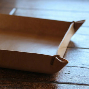 Brown leather tray on a wooden surface