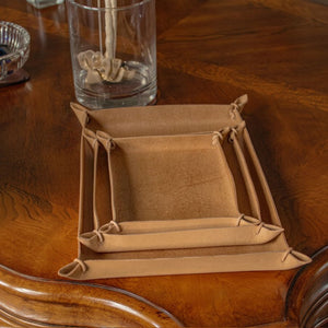 Brown leather tray on a wooden surface with a glass of water and a small bowl.