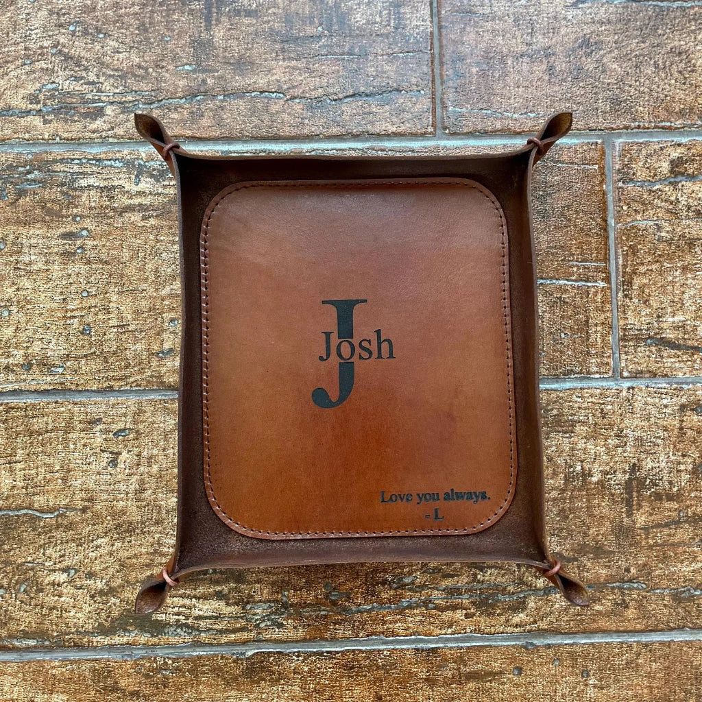 Brown whiskey leather tray with name and initials engraving on a wooden surface