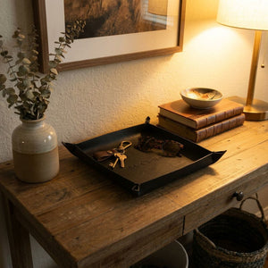 Decorative tray with keys on a wooden table next to a lamp and books