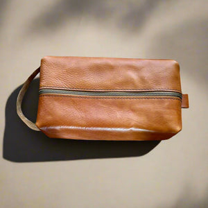 Handmade Dopp kit in premium tan Italian leather, shown in medium size. Customizable with an engraved name.