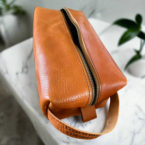 Handmade Dopp kit in premium tan Italian leather, shown in large size. Customizable with an engraved name.