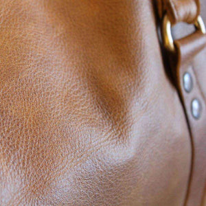 Close-up of a brown leather handbag with a gold buckle.