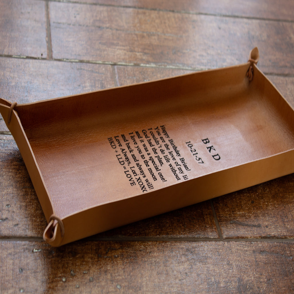 Text is engraved on a handcrafted oblong tray made of Italian full-grain leather in natural color.