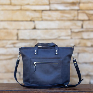 Large tote bag in black-colored Italian leather, handcrafted with a front double-zip pocket, a top zipper closure and a long detachable strap, for added convenience. A unique, timeless gift for yourself or a loved one.