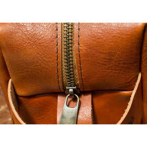 Close-up of a handmade Dopp kit in premium tan Italian leather, shown in medium size. 