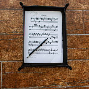 Sheet music in a black Italian leather  A4-sized tray on a wooden surface