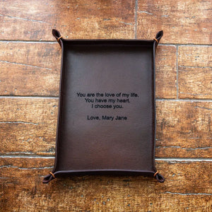 Brown leather tray with a romantic message on a wooden surface