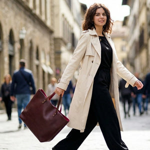 Woman walking down a city street holding a brown leather tote.