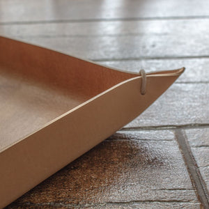 A view of an oblong tray made of Italian full-grain leather in a natural color.