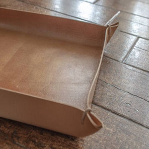 View of a natural-colored, large size Italian leather tray with leather cords at each corner