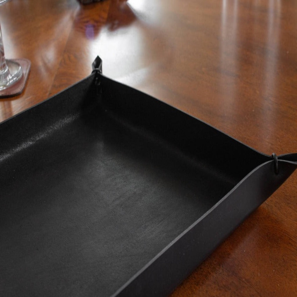View of a black-colored, large size Italian leather tray with leather cords at each corner